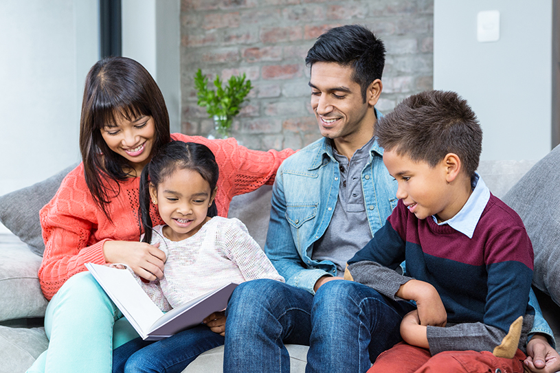 Happy young family reading a book together in living room